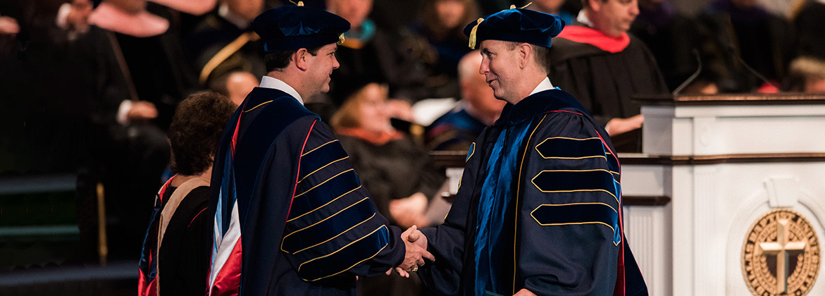 Dr. Wright is shaking hands with a graduating doctoral student. 