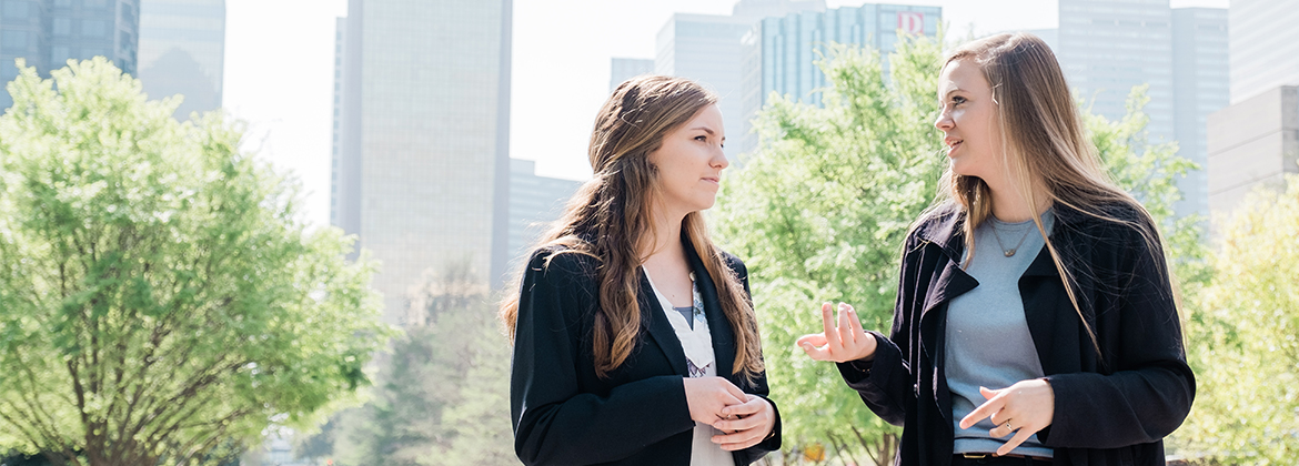 Two women talk against the Dallas skyline