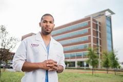 student standing in front of hospital with white dbu lab coat 