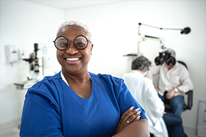woman with glasses and blue scrubs smiling in front of patient