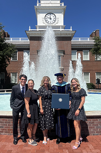 Dr. Chevalier standing in front of the Mahler Student Center fountain with his family at graduation