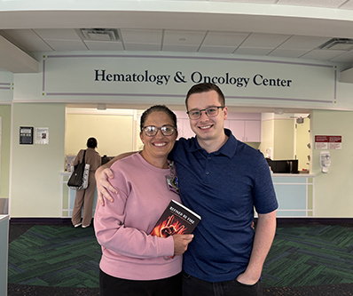 Christian Englert standing with a woman in a hospital lobby under the "Hematology & Oncology" sign