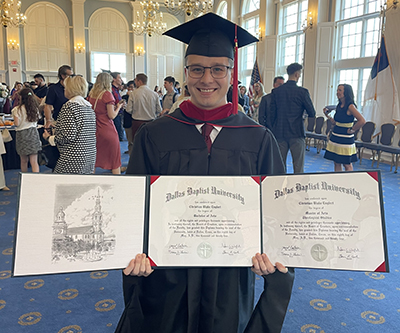 Christian Englert holding his bachelor's and master's degrees diplomas
