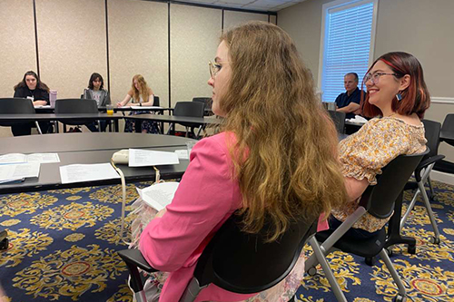 college students seated in a meeting room in a circle, listening during a small group discussion