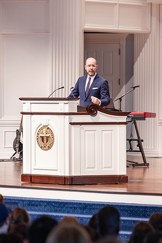 Knox Thames speaking on stage during Chapel to college students at a Christian university