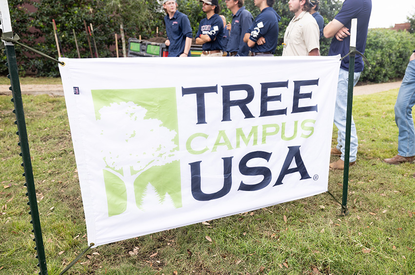 Tree Campus USA banner with grounds crew in the background
