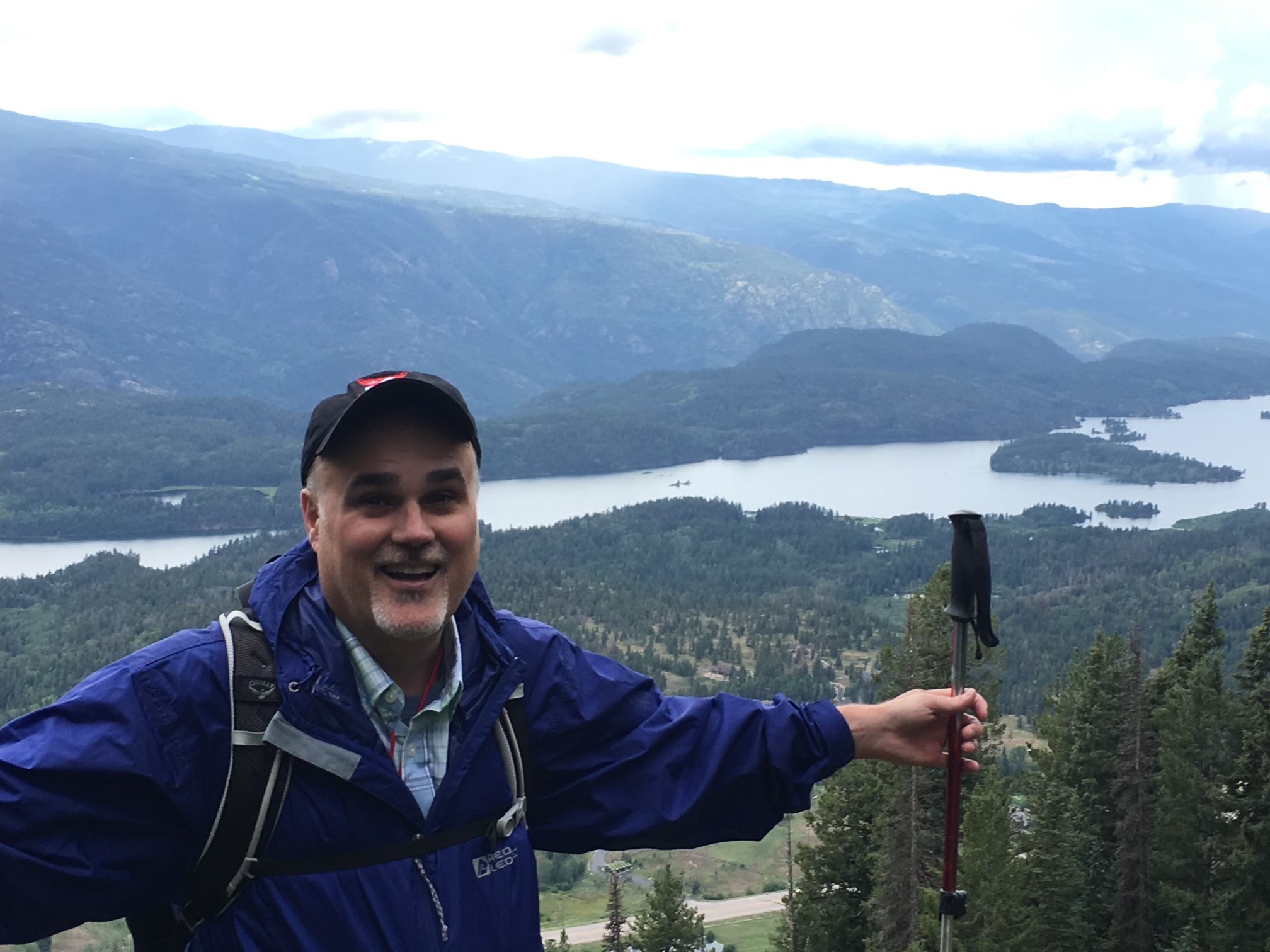 Ed Fry with a trekking pole on a mountain overlooking a lake