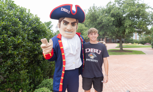 girl taking a picture with DBU mascot by the bell in mahler student center