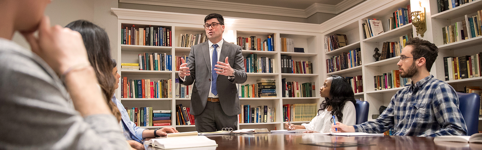 professor teaching college students around a table