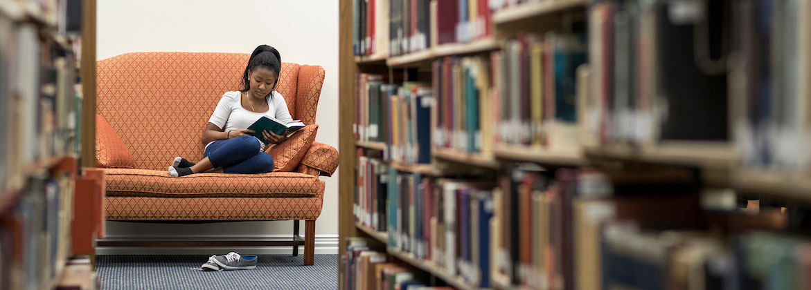 student reading a literature book in the dbu library