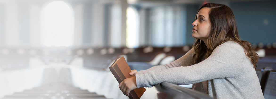 Girl sitting in a chapel while holding a Bible