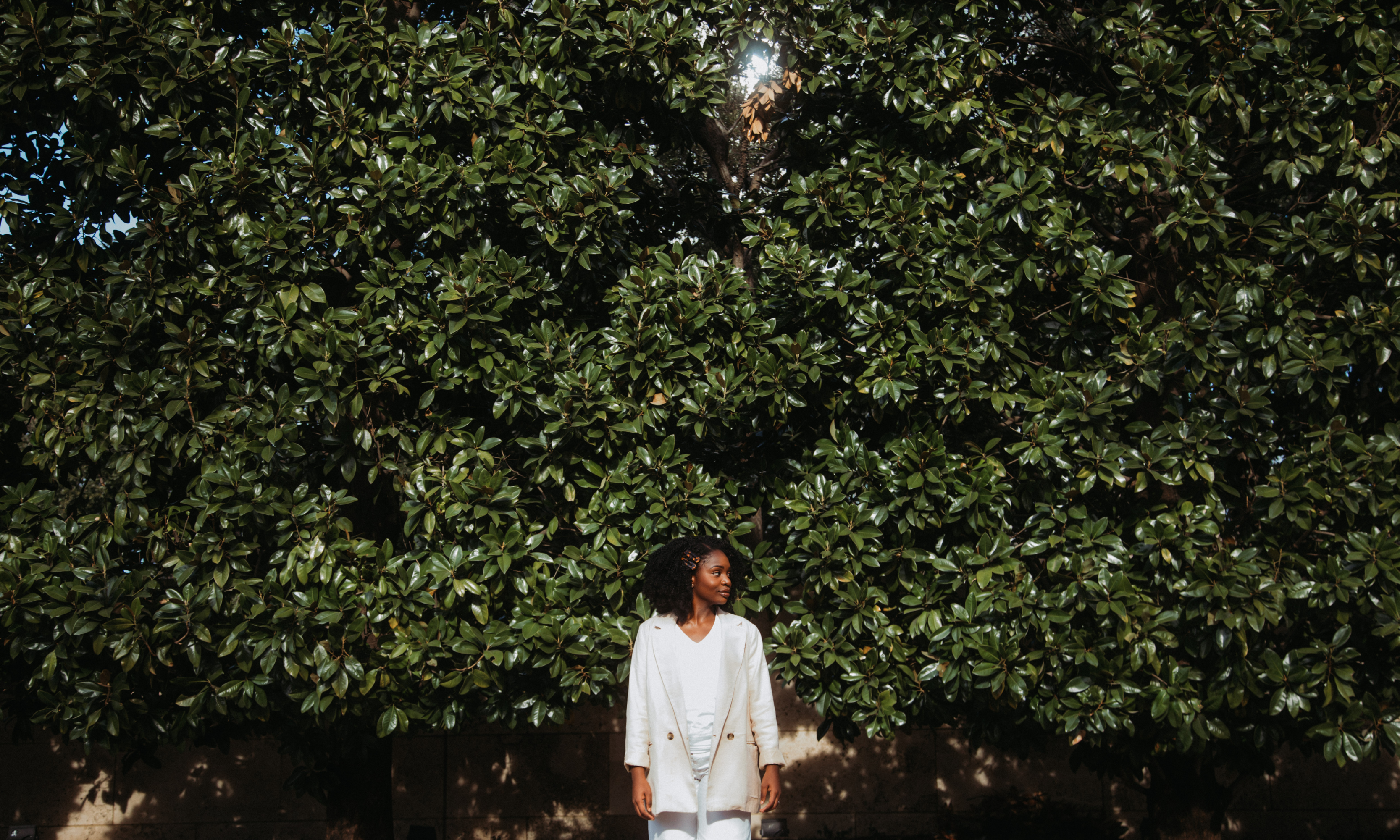 female student standing outside with greenery behind her in the background