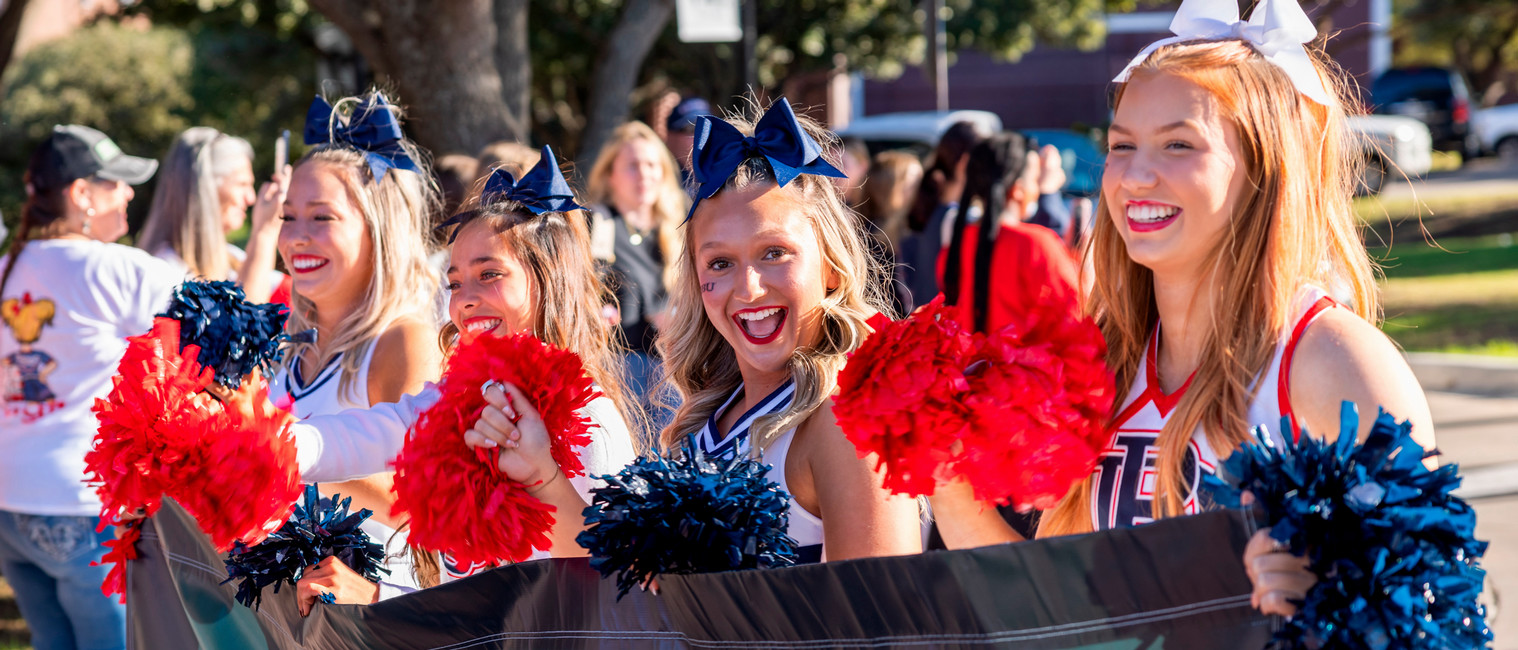 DBU cheerleaders excited walking in homecoming parade around campus buildings