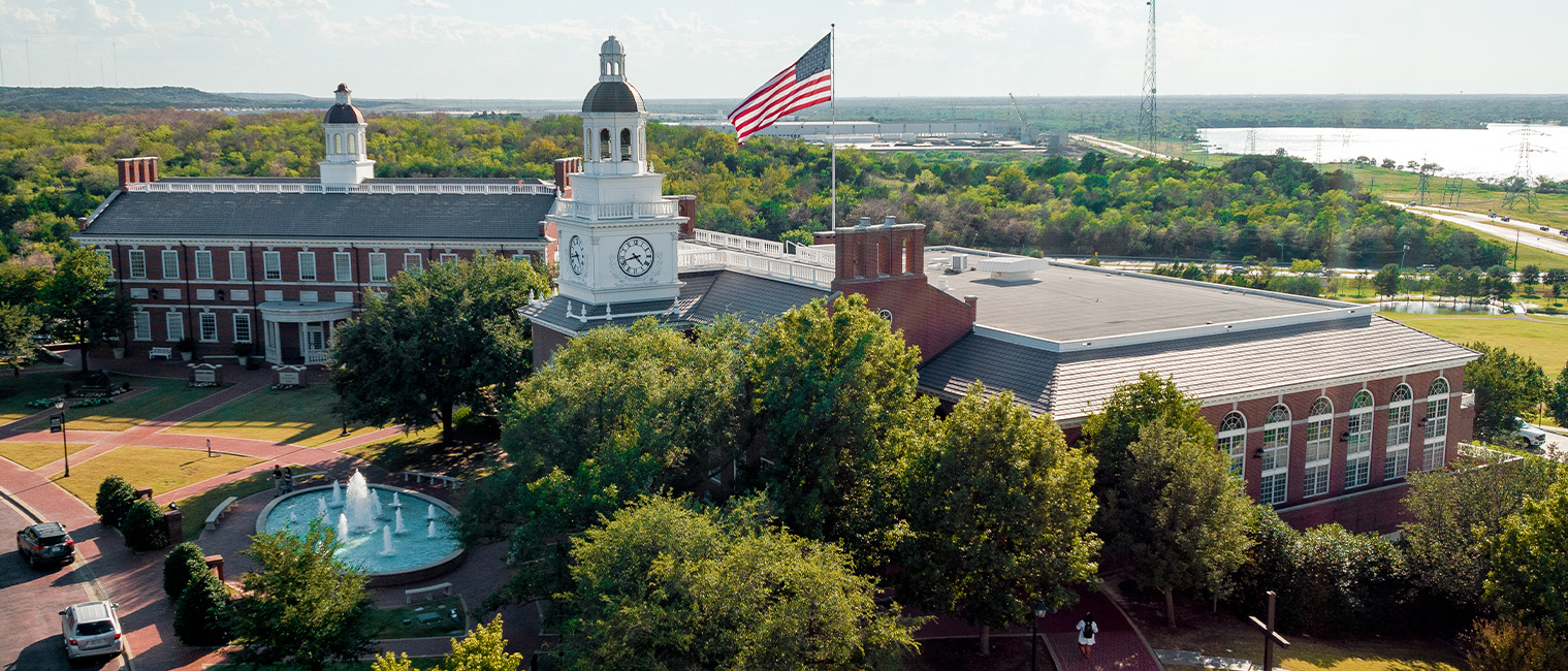 view of a red-brick campus building with a clock tower and fountain in front