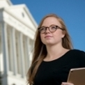 honors student outside looking up with chapel behind her