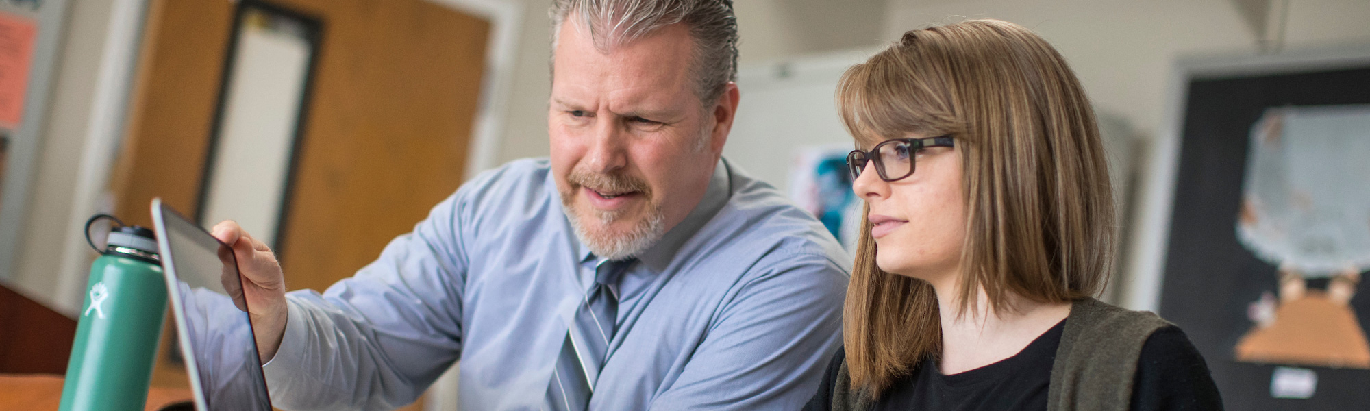 a professor and student talk in a classroom