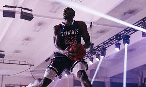 dbu patriots student athlete jumping in air to slamp dunk the basketball into the basketball basket