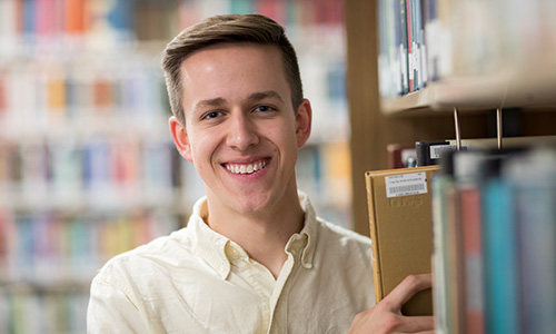 a boy holds a book in the library