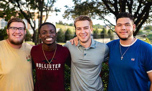 4 college guys group picture near upperclassmen housing facilities