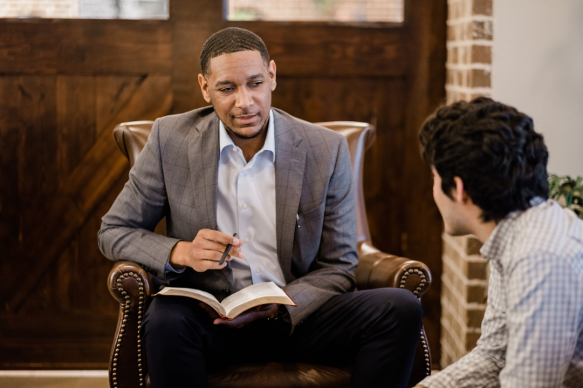 A man and young man talk in a coffee shop