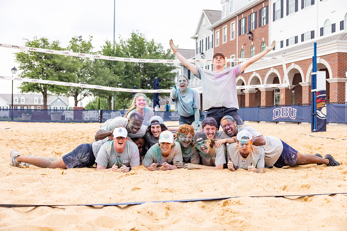 dallas college students covered in color paint posing in volleyball court for a photo