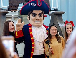 dbu students taking a picture with the patriot man after ringing the bell