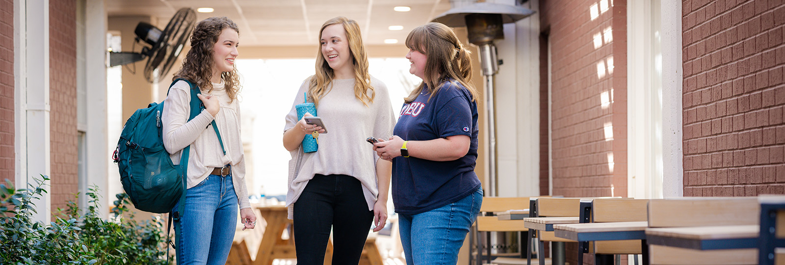 Three undergraduate students talking on campus