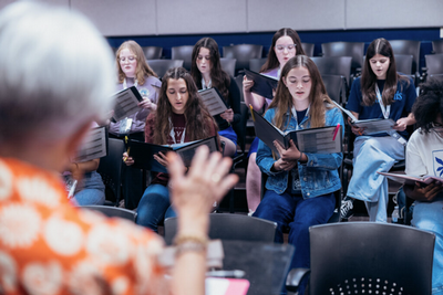 choir-camp-2.png a classroom of high school students practicing with a music instructor