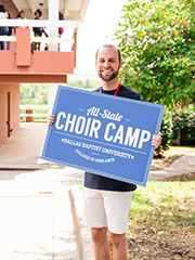 guy holding all state choir camp sign outside at DBU