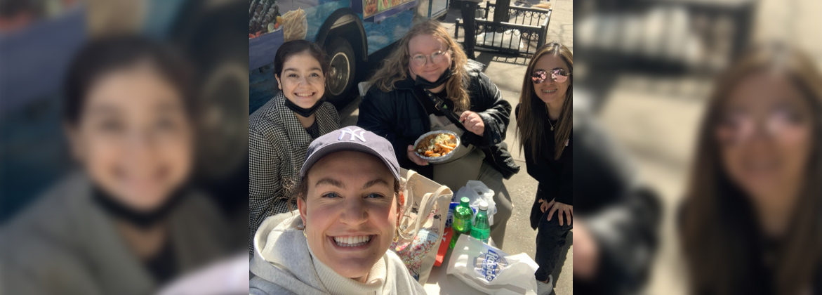 Students pose while eating in front of a food truck in New York