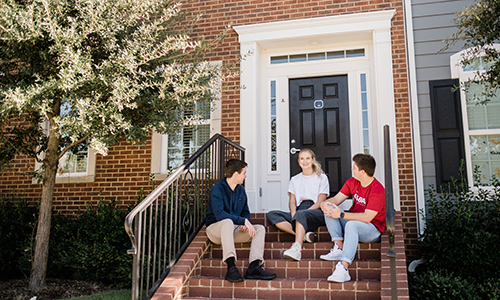 a group of students sitting on the front porch of a brownstone