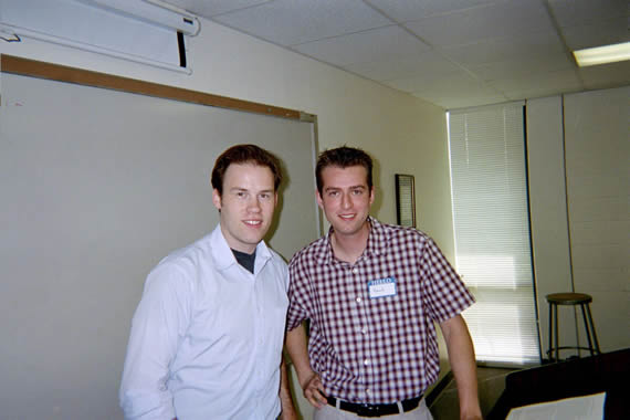 two men standing next to each other smiling in front of a podium in classroom