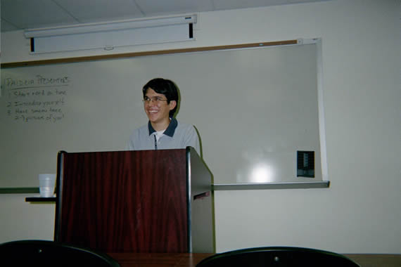 picture of a man wearing glasses smiling behind a podium