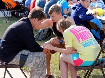 DBU students Chase Thomson (center) and Jessica Kowalski (right) pray with a student during Beach Reach 2013 in South Padre Island.