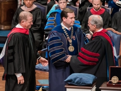 Dr.Wright is standing on stage shaking hands with a man.