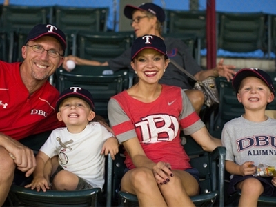 Dr. Gandy, Professor of Management, smiles alongside his wife and two sons at the ball game
