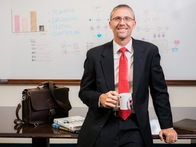 Dr. Justin Gandy in front of a whiteboard displaying management tactics