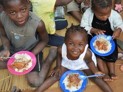 A sweet baby girl eats with her friends in Mozambique