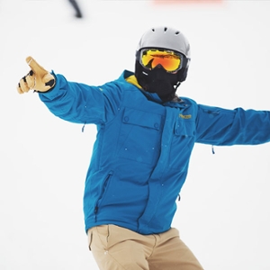3. A person with a blue jacket and a gray helmet pointing off to the distance. The background is completely white, and the person’s ski goggles are reflective and yellow.