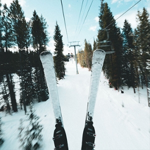 2. A picture of two skis on a ski lift, vertical and covered in snow, with tall trees off to the side