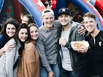 students pose in front of a bouncy house at the block party on the hill