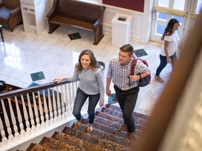 Students climb the stairs in the Spence dorm lobby