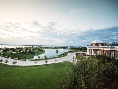 Overlooking campus from the Chapel balcony with Nation Hall and Swan Lake lit by the sunset on the horizon