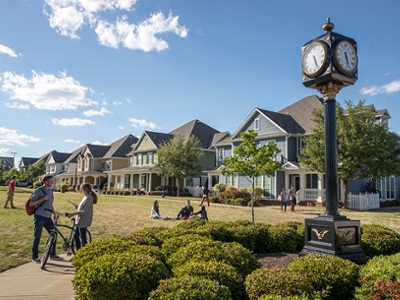 Students talk, have a picnic, play football, and walk to class on the yard in between the townhomes on campus.