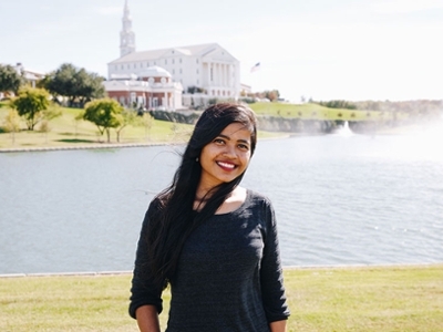 Ranjita poses in front of swan lake with the chapel and nation hall in the background.