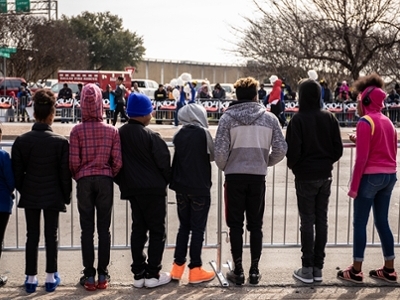 8 young children are standing in a row, waiting for a parade to begin. 