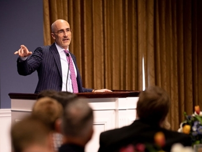 A man is standing at a podium speaking. 