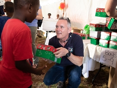 A DBU Faculty Member is handing a box to young boy. 