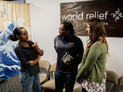 A DBU Student is standing with two women at World Relief in Fort Worth.