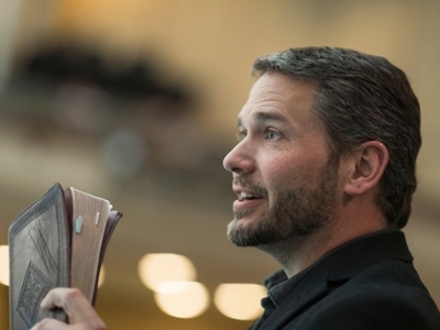 A man is standing holding a bible.